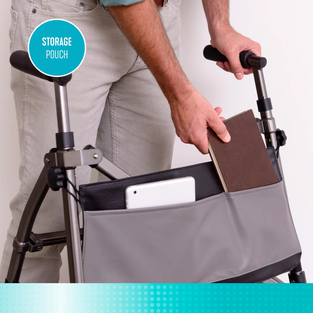 A person places a book into the storage pouch of the Signature Life Elite Bariatric Travel Walker, which already has a tablet inside. A turquoise label in the image reads STORAGE POUCH.