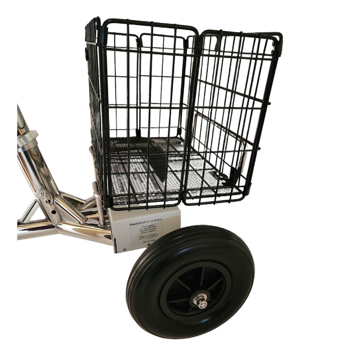 Close-up of a black wire shopping cart with one large rubber wheel and metal frame, featuring an instruction plaque with specifications. Background is white. Product: SmartScoot® Ultra Light Mobility Scooter - FAA Approved.