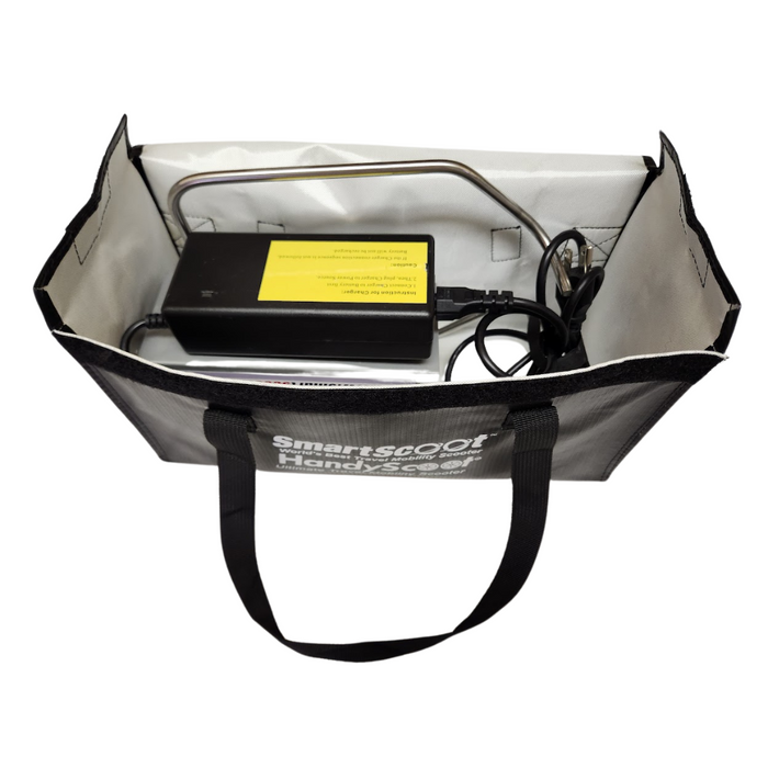 The black and gray SmartScoot Handybag, ideal for holding a Scooter Cover, includes a charger with a yellow label. It features two handles and has SmartScoot Handybag printed in white on the side. The charger connects to a power cable inside the bag.