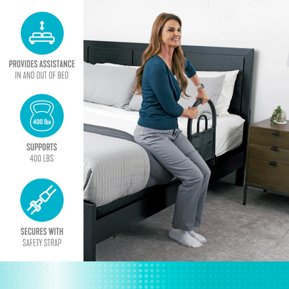 A woman uses the Stander Bed Rail Advantage Traveler, a black portable safety rail, while sitting on a made bed. Graphics show its bariatric support handle assists users, supports up to 400 lbs, and secures with a safety strap.