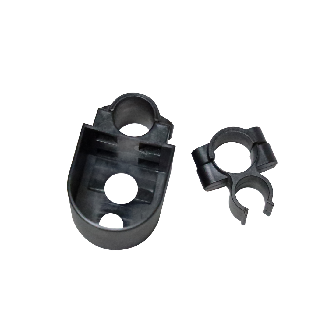 Two small black plastic accessories from the Step2bed Deluxe Bedside Step-Up Platform kit—a U-shaped clip and an oval-shaped piece with circular holes—are shown on a white background.