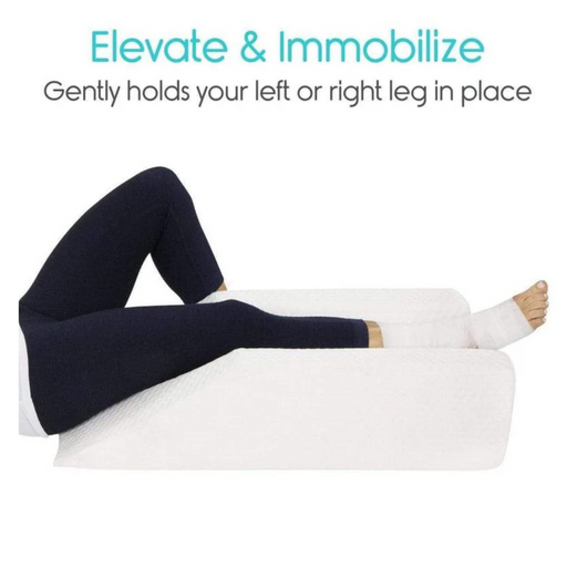 A person is lying down with their left leg wrapped in a bandage, elevated on the Vive Health Knee Elevation Foam Pillow - Xtra-Comfort. Text reads, Elevate & Immobilize: Securely holds your left or right leg for surgery recovery. Theyre wearing dark leggings to help reduce swelling.