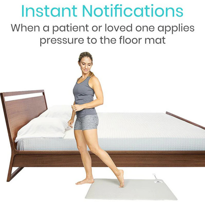 A woman in athletic wear stands on a floor alarm mat next to a bed. Text above reads Real-Time Alerts: When a patient or loved one applies pressure. The scene illustrates the Vive Health Wireless Floor Alarm Mat & Transmitter, ideal for monitoring bed exits.