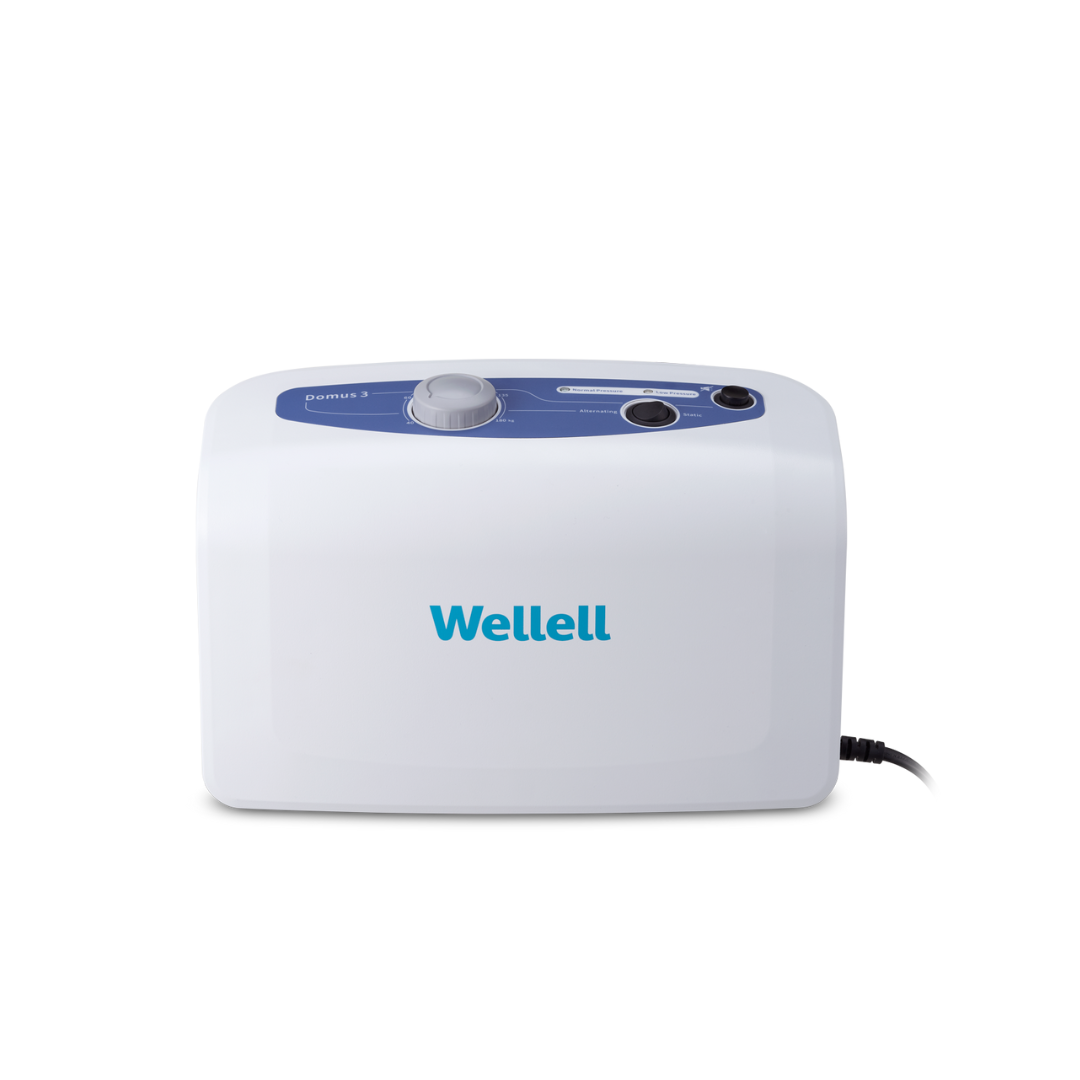 The Wellell Domus 3 Bariatric Alternating Pressure Mattress with Micro Low Air Loss is a white device with a blue control panel, dial, and buttons, plugged in on the right side, designed for pressure ulcer prevention.