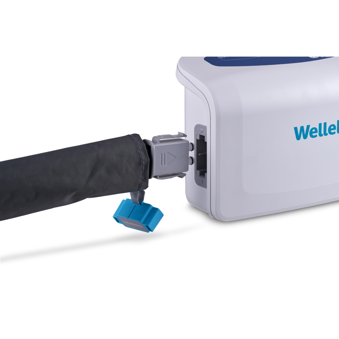 A close-up of the Wellell Domus 4 Bariatric Alternating Pressure Mattress with Micro Low Air Loss shows a black tube and blue connector being attached to the unit.
