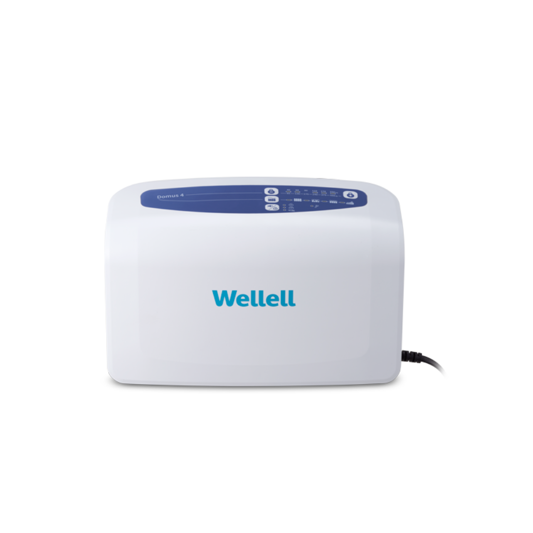 The Wellell Domus 4 Bariatric Alternating Pressure Mattress with Micro Low Air Loss is a white medical device featuring a blue top display panel and Wellell branding, designed for pressure ulcer prevention in post-acute care, with a right-side power cord.