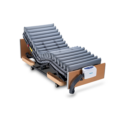 The Wellell Domus 4 Bariatric Alternating Pressure Mattress with Micro Low Air Loss features an adjustable bed, inflatable grey mattress, alternating pressure system, wood panels, wheels, and a control unit—ideal for pressure ulcer prevention in post-acute care.